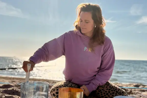 AK Feldkamp Eine Frau sitzt auf einer Decke am Strand.