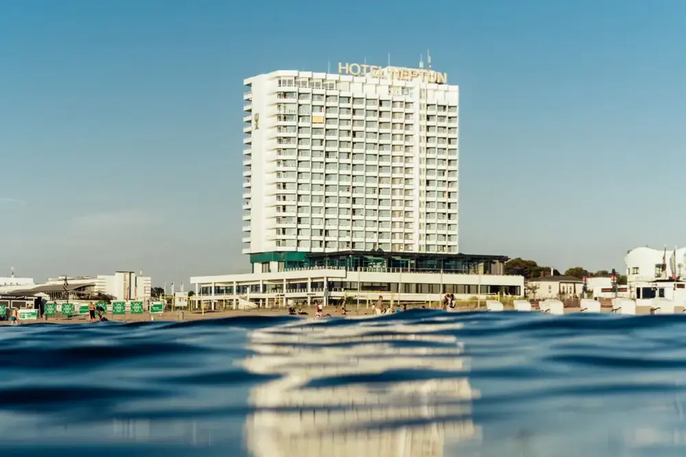 Hotel NEPTUN Warnemünde Modernes Hochhaushotel direkt am Wasser mit klarem blauen Himmel im Hintergrund