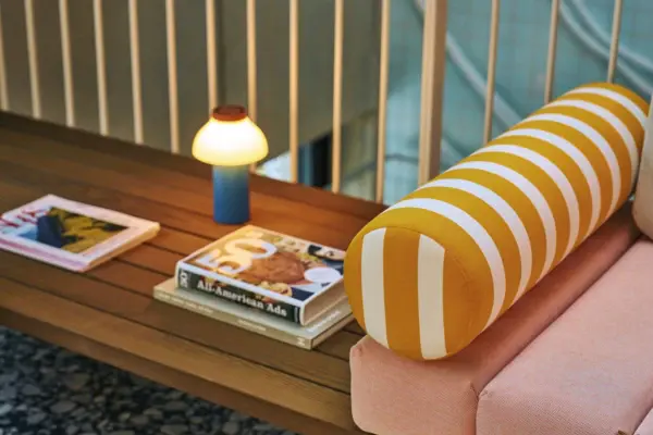 Loungebereich Alpine Swim Club Detailaufnahme einer Design-Sitzbank mit gestreifter Rolle, stilvoller Tischleuchte und Lifestyle-Magazinen im modernen Loungebereich