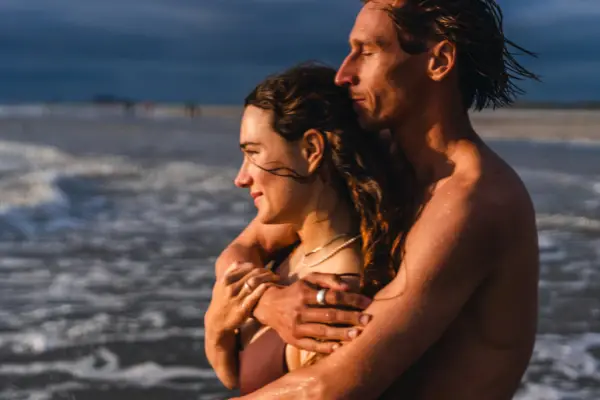 Menschen Strand St. Peter-Ording Ein Mann umarmt eine Frau am Strand und beide schauen auf das Meer.