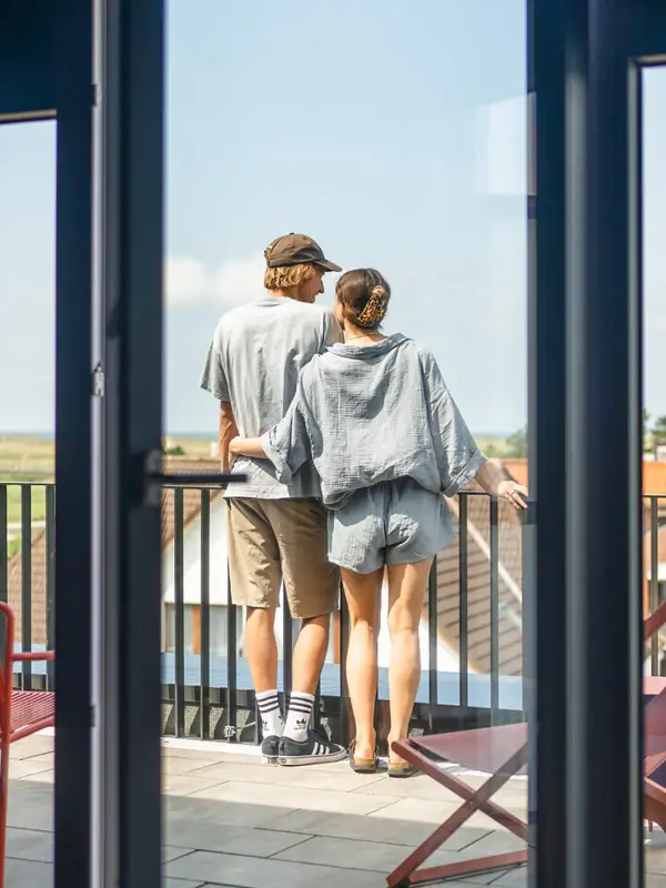 Zimmer St. Peter-Ording Ein Mann und eine Frau stehen auf einem Balkon und genießen die Aussicht.