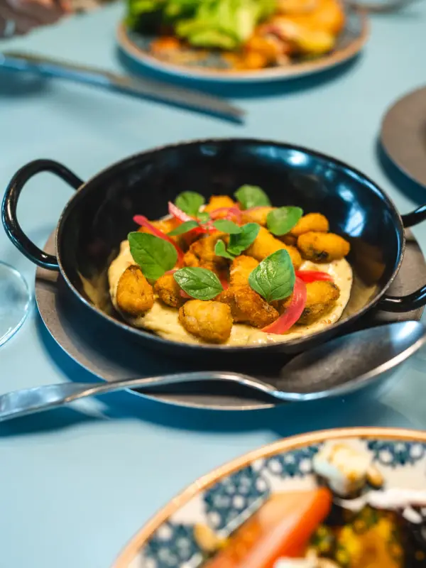 Pfännchen Auntie Clara Eine Speise ist in einem kleinen Fännchen angerichtet und mit Basilikum verziert.