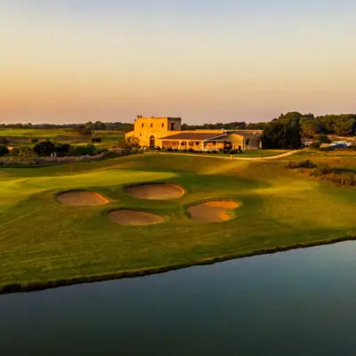 Acaya Golf Resort & Spa Ein Haus steht hinter einem Golfplatz bei Sonnenuntergang.