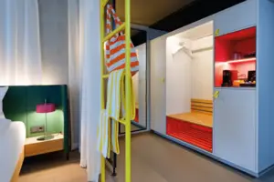 Doppelzimmer Comfort Ein Raum mit einer gelben Leiter und einem rot-weißen Bett.