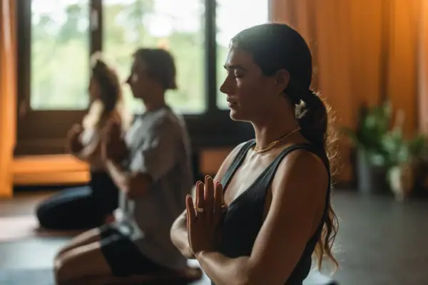 Yoga Urban Nature St. Peter-Ording Eine Frau in einem schwarzen Top macht Yoga mit vor dem Körper zusammengelegten Händen.