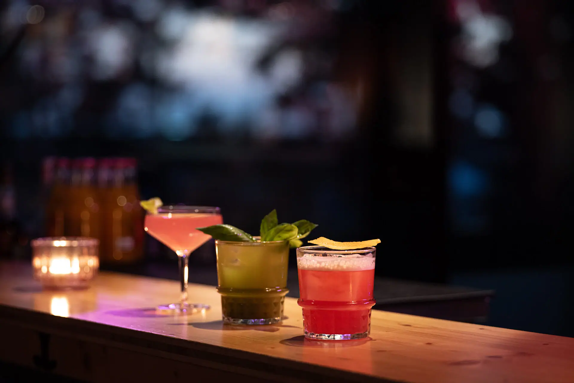 Eine Auswahl an Cocktails mit Garnitur auf einer Bar.