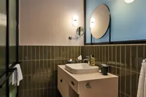 Juniorsuite Straubinger Platz Ein Badezimmer mit einem Waschbecken und einem runden Spiegel.