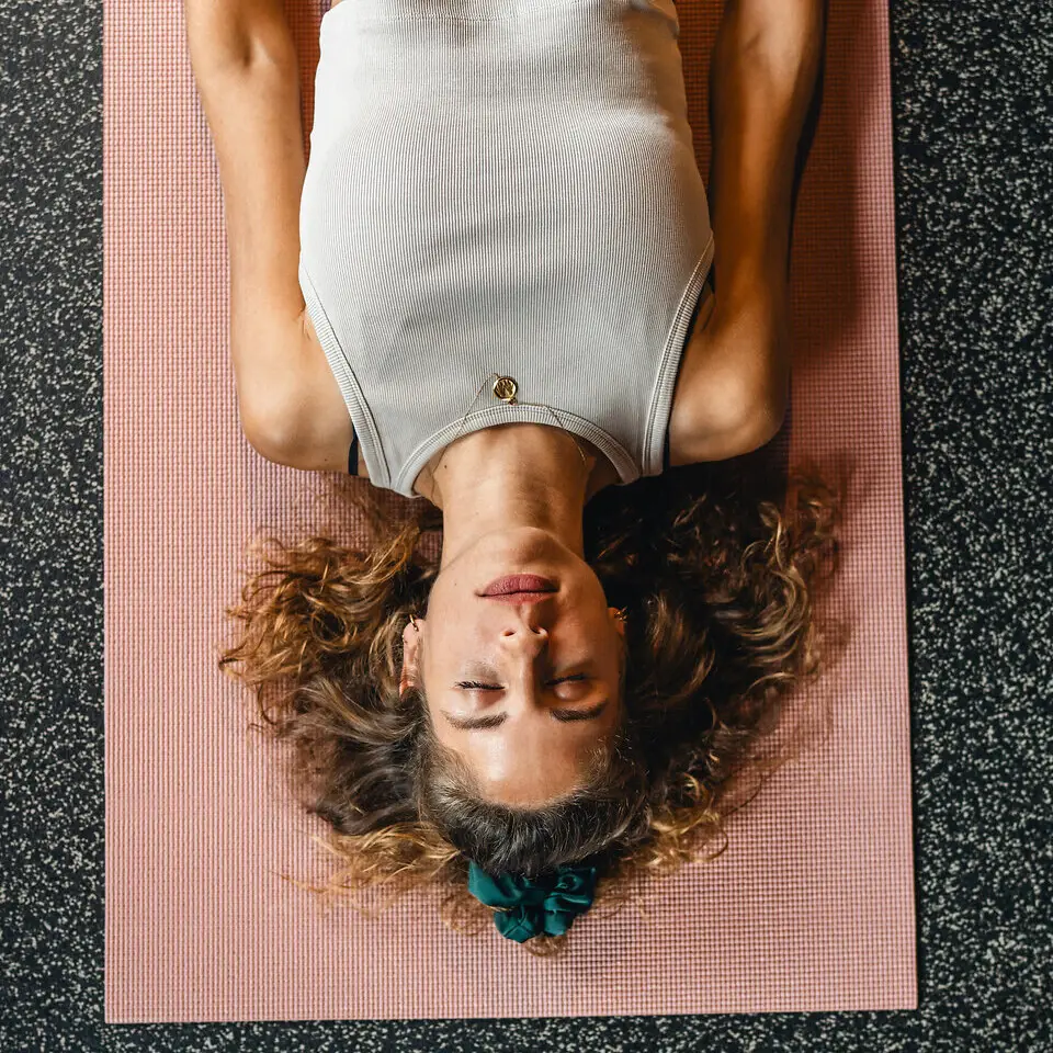 Yoga Urban Nature St. Peter-Ording Eine Frau liegt auf einer Yogamatte und hat die Augen geschlossen.