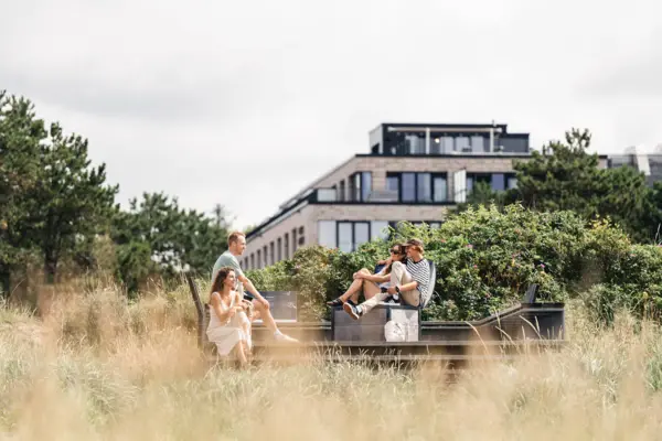 Urban Nature St. Peter-Ording Eine Gruppe von Menschen sitzt auf einer Bank im Freien.