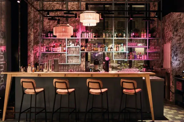 Drifters Hang Out Bar Eine Bar mit einer Reihe von Hockern und Lichtern.