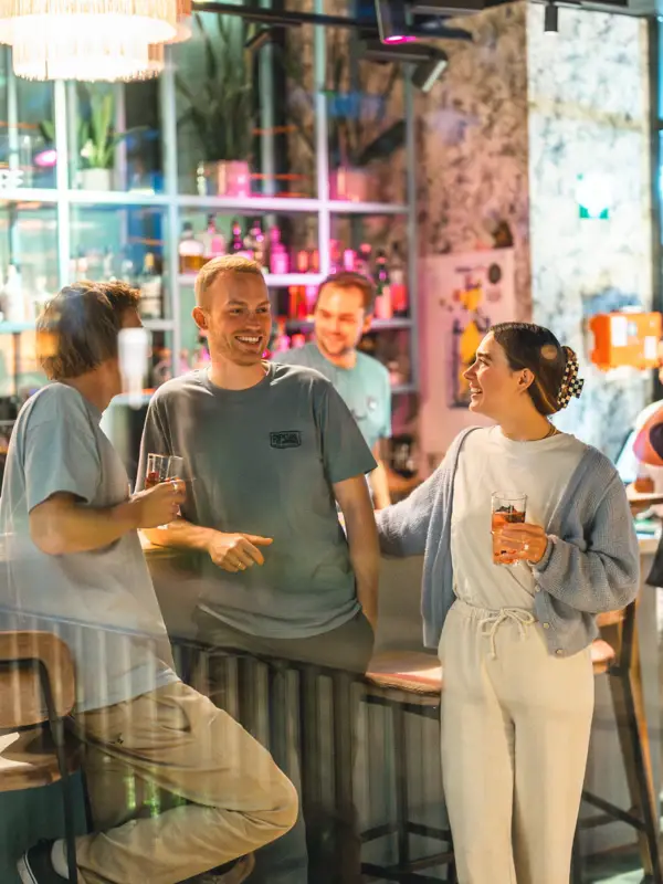 People Drifters Hang Out Mehrere Menschen stehen an einer Bar und unterhalten sich mit Getränken in der Hand.
