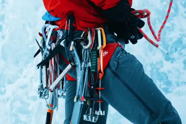 Eisklettern Bad Gastein Person in roter Jacke mit Kletterausrüstung im Schnee und Eis.