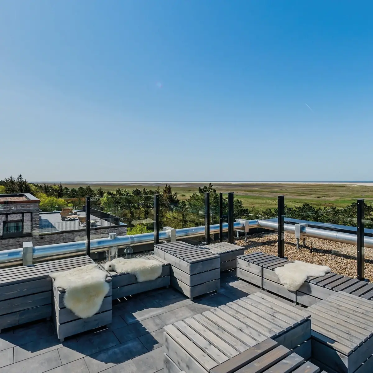 Scraper’s Club St. Peter-Ording Eine Dachterrasse mit Holzmöbeln und einem tollen Ausblick über die Salzwiesen bis hin zur Nordsee von St. Peter-Ording.