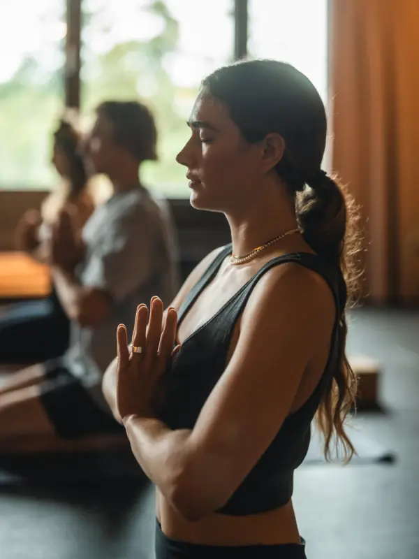 Yoga Urban Nature Hotel St. Peter-Ording Eine Frau in einem schwarzen Top macht Yoga mit vor dem Körper zusammengelegten Händen.