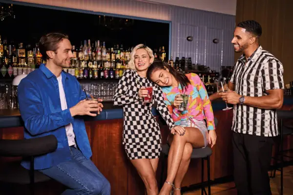 Party Bar Bad Gastein Eine Gruppe von Menschen stehenmit Getränken in der Hand an einer Bar und lachen.