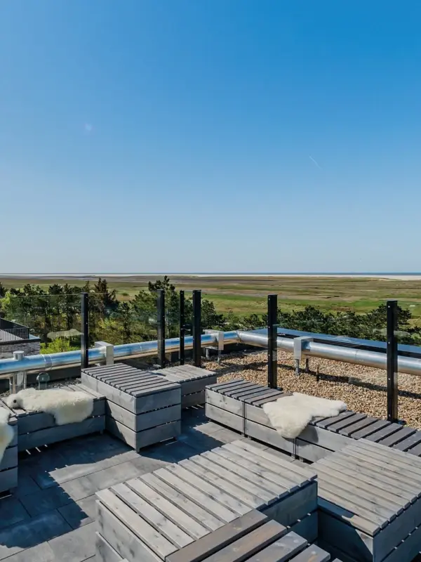 Rooftop Bar St. Peter-Ording Die Rooftopbar Scraper's Club im Urban Nature Hotel St. Peter Ording mit Bänken und Tischen aus Holz.