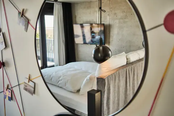 Zimmer Spiegel in einem Schlafzimmer mit Bett und Bettwäsche.