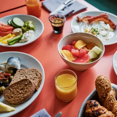 Frühstückstisch Auntie Heidi Ein Frühstückstisch mit Speisen wie Obst, Brot, Eiern und Orangensaft.