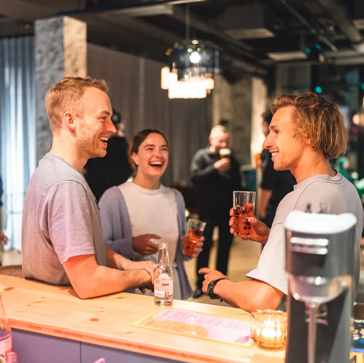 People Drifters Drei Personen stehen an der Bar im Drifters Hang Out und haben einen Drink in der Hand.