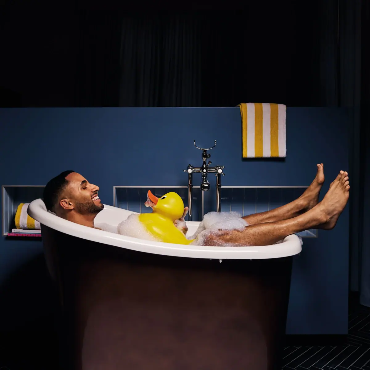 Badewanne Ein Mann liegt in einer Badewanne mit einer Gummiente.
