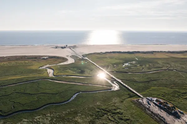 Strand Ein Weg, die zu einem Strand führt, mit Himmel und Wasser im Hintergrund.
