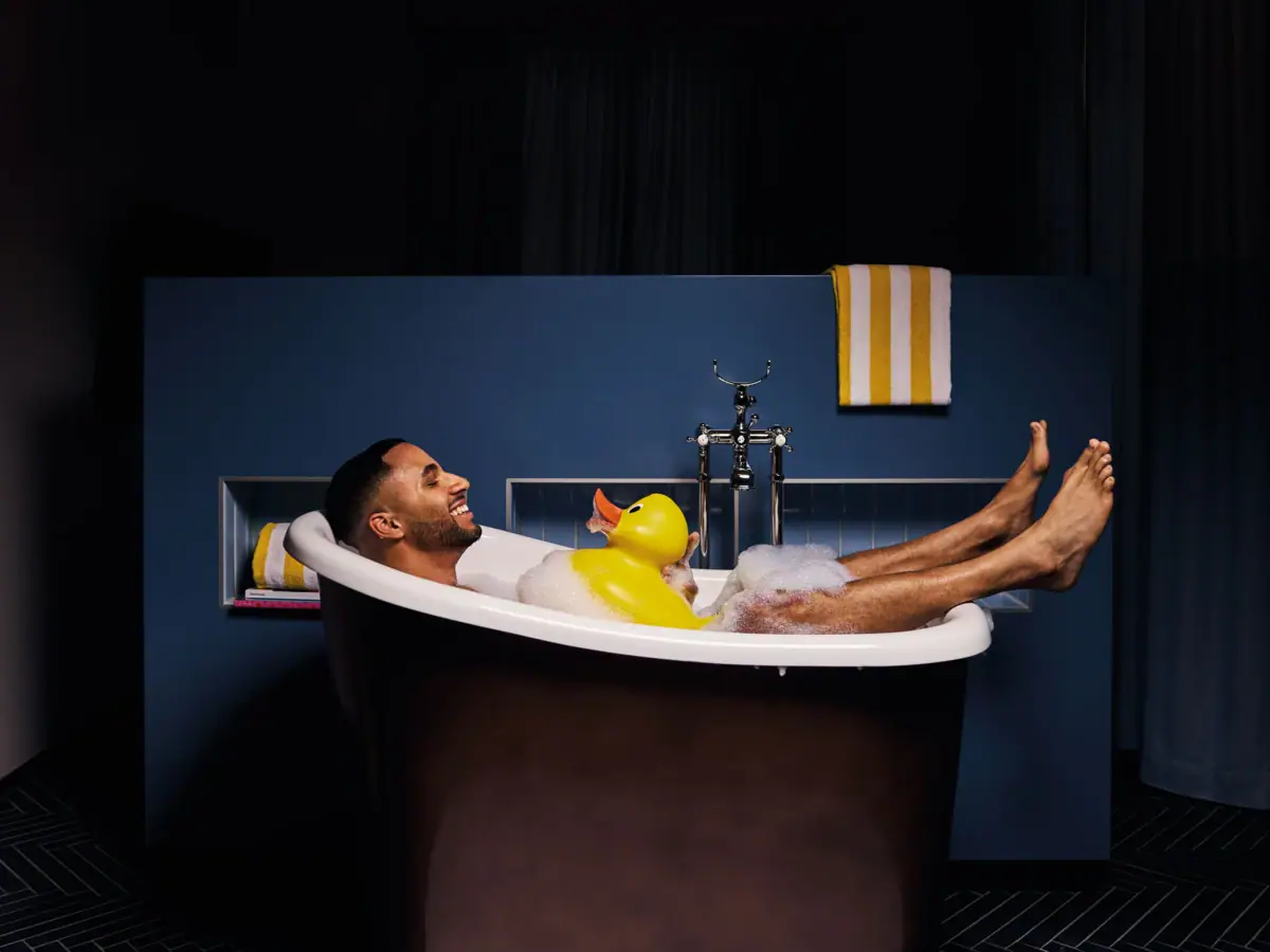 Badewanne Ein Mann liegt in einer Badewanne mit einer Gummiente.