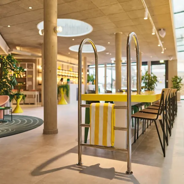 Lobby im Urban Nature Hotel im Badeschloss Bad Gastein Kreatives Interior im Hotel:Modern gestalteter Rezeptionsbereich mit Schwimmbadleiter als Designelement, gelb-weißen Akzenten und stilvollen Sitzgelegenheiten.