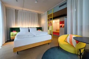 Doppelzimmer Comfort Ein Zimmer mit einem Bett und einem gelben Stuhl.