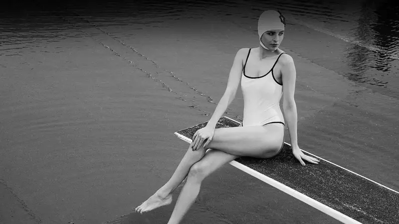 Frau Badeanzug Eine Frau in Badeanzug und mit Badekappe sitzt auf eine Springbrett.