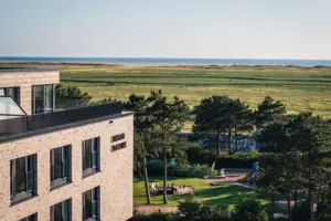 Urban Nature St. Peter-Ording Ein Gebäude mit einem Spielplatz und einem Grasfeld.