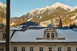 Ausblick Ein Gebäude mit Schnee auf dem Dach und Bergen im Hintergrund.