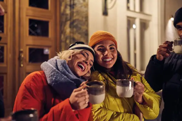 Glühweintrinken Eine Gruppe von Frauen hält Tassen.