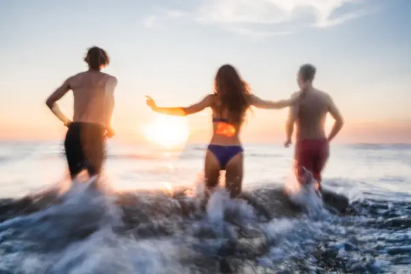 Nordsee St. Peter-Ording Eine Gruppe von Menschen springt ebi Sonnenuntergang in die Wellen der Nordsee.