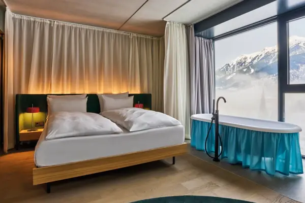 Zimmer Bad Gastein Ein modernes Hotelzimmer mit einem Bett und einer freistehenden Badewanne.