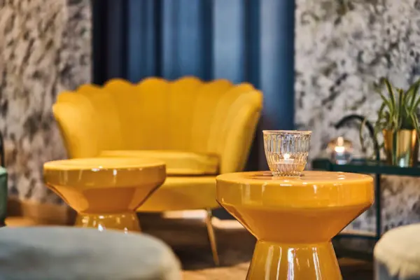 Sessel Drifters Hang Out Gelber Stuhl und Glas-Kerze auf einem gelben Tisch.