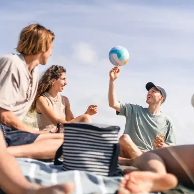 Strand People St. Peter-Ording Eine Gruppe von Menschen sitzt am Strand und spielt mit einem Volleyball herum.