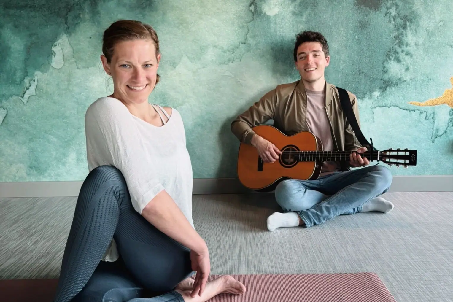 Yoga Retreat Sara und Till Ein Mann und eine Frau sitzen auf dem Boden mit einer Gitarre.