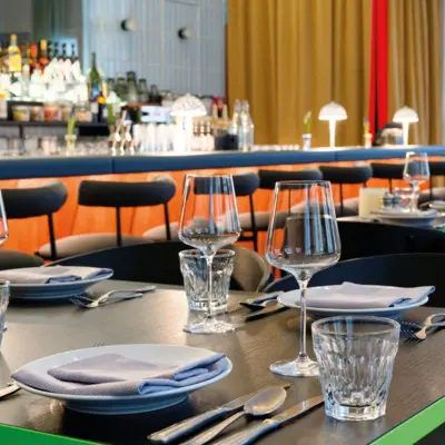 Tisch Auntie Heidi Ein eingedeckter Tisch in einem Restaurant mit Tellern, Gläsern und Servietten.