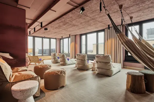 Wellness Urban Nature Ein Ruheraum mit gemütlichen Sitzmöglichkeiten, Hängematten und großen Fenstern.