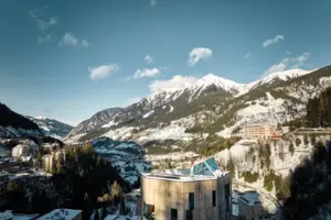 Urban Nature Bad Gastein Ein Gebäude mit Dach vor schneebedeckten Bergen im Hintergrund.