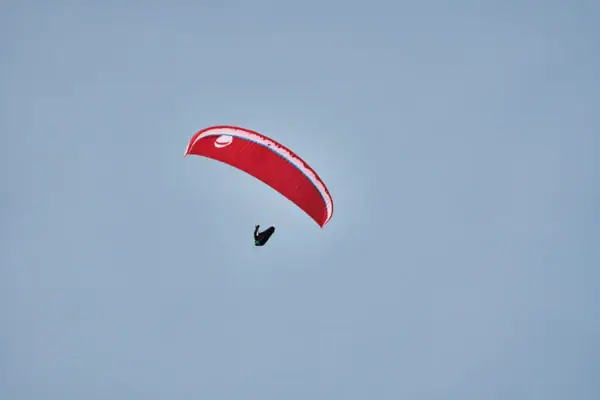 Paragliden Eine Person beim Paragliden vor einem blauen Himmel.