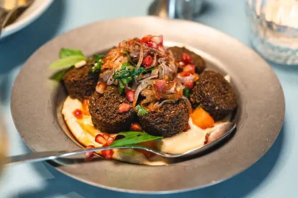 Tellergericht Auntie Clara Ein Teller von oben fotografiert auf dem eine leckere Speise mit Falafel angerichtet ist.