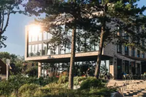 Urban Nature St. Peter-Ording Ein Gebäude mit Bäumen und einer Gruppe von Menschen davor.