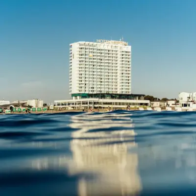 Hotel NEPTUN Warnemünde Modernes Hochhaushotel direkt am Wasser mit klarem blauen Himmel im Hintergrund