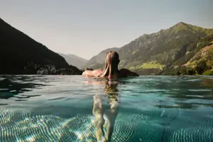 Außenpool Eine Frau schwimmt in einem Pool mit Bergen im Hintergrund.