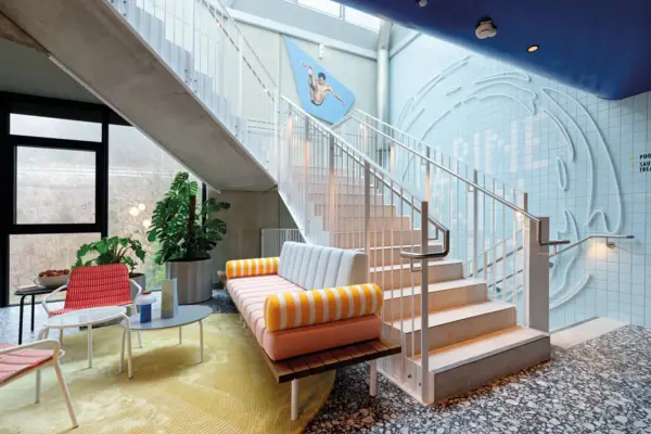 Loungebereich Alpine Swim Club Design-Lounge mit bunter Sitzbank, farbenfroher Wandgestaltung und moderner Treppe in stylischem Hotelambiente