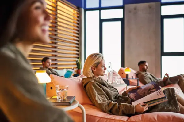 Ruhebereich Urban Nature Bad Gastein Mehrere Personen liegen in gemütlichen Sesseln in einem Ruhebereich und tragen Bademäntel.