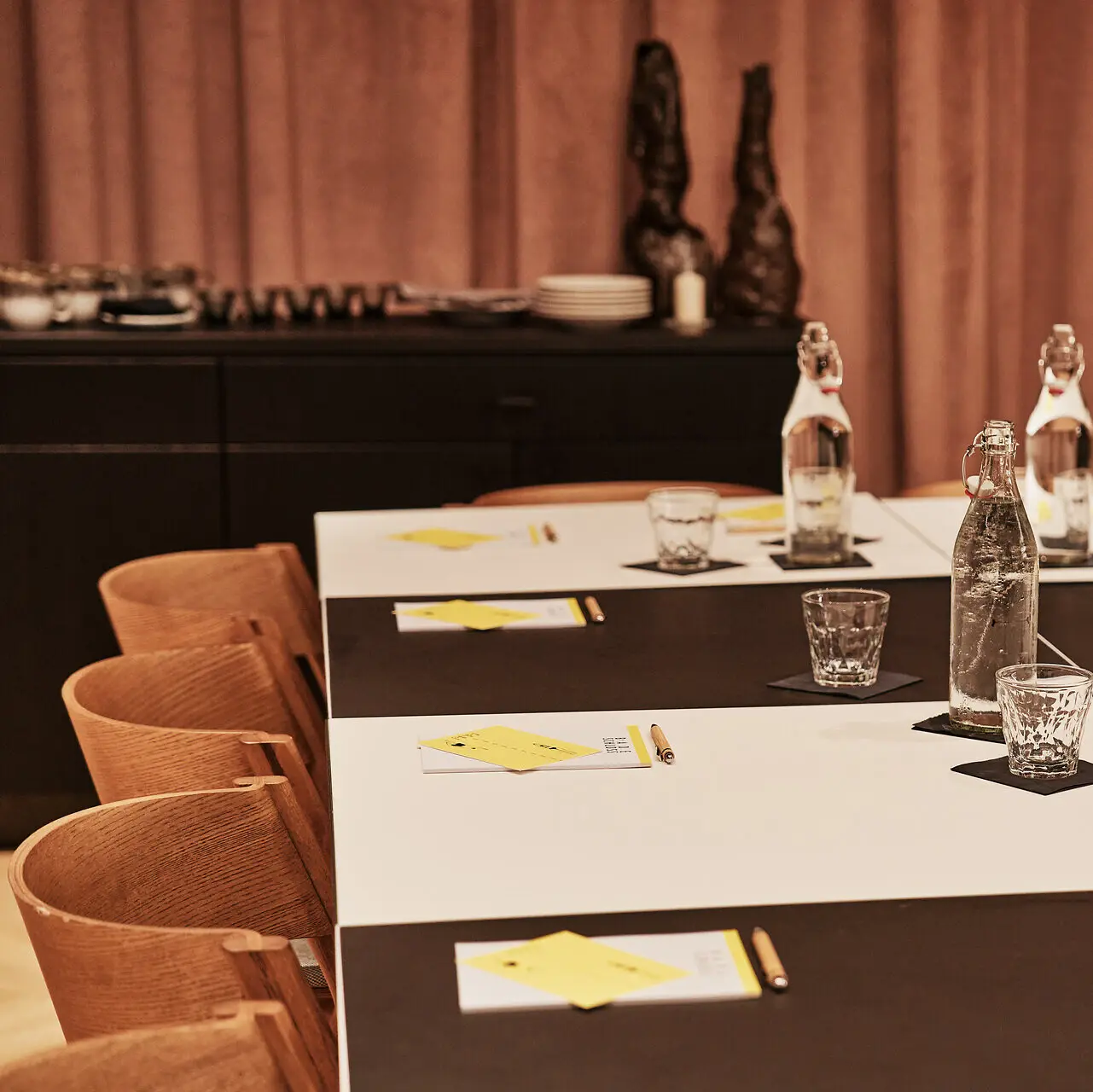 Meetingsraum Bad Gastein Ein Tisch in einem Meetingraum ist mit Blöcken und Wassergläsern eingedeckt.