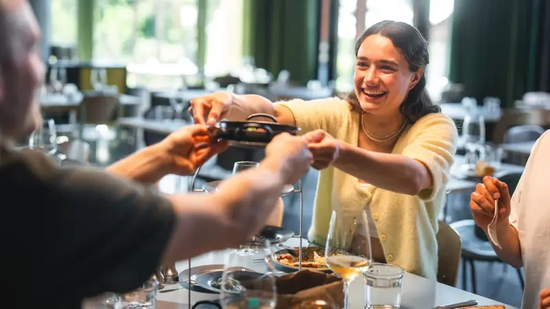 Sharing im Auntie Clara Restaurant Mehrere Menschen sitzen an einem Tisch und reichen sich Speisen zum Teilen.