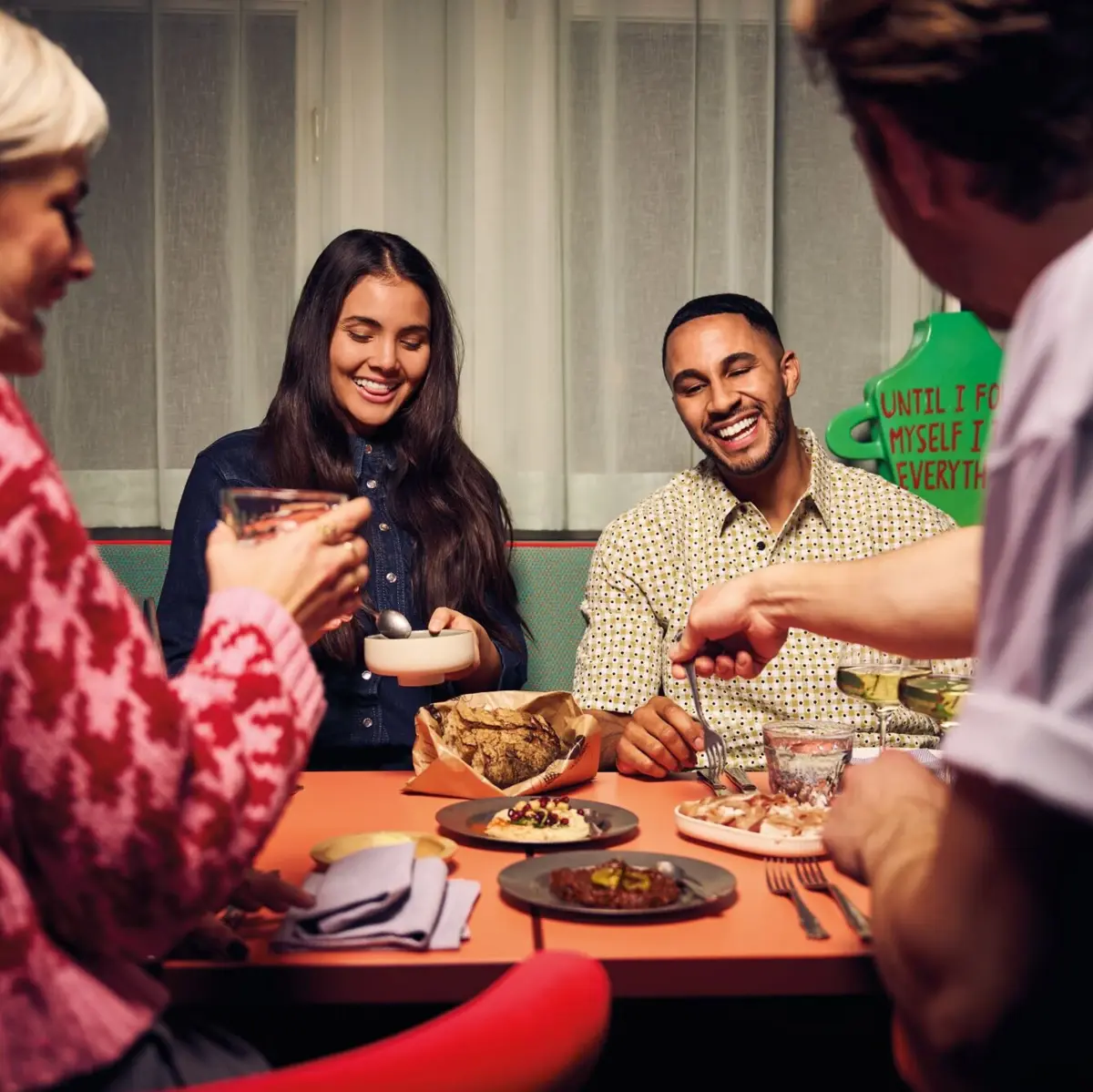 Mittagessen im Restaurant Auntie Heidi Gruppe junger Menschen beim gemeinsamen Essen – Lachen, Teilen und Genießen in geselliger Runde